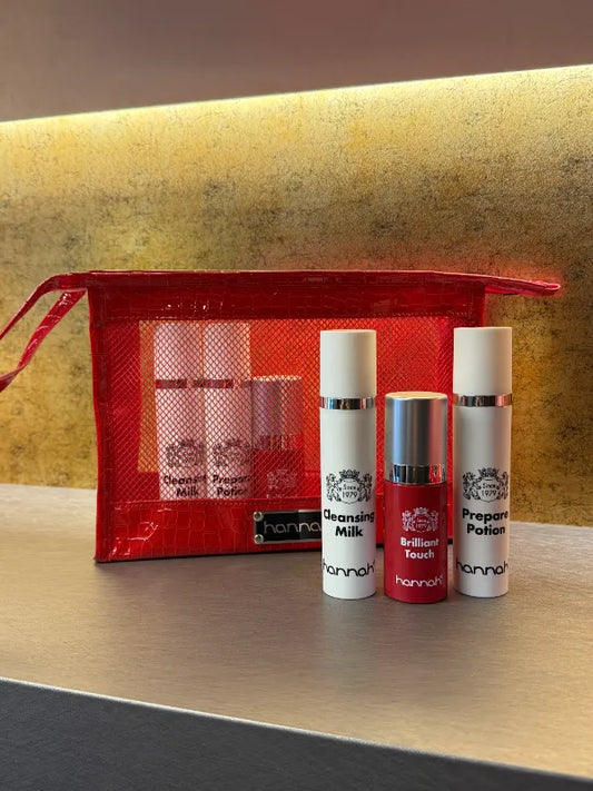 hannah Travel in Style mini reisset voor wie de vaste huidroutine mee wil nemen zonder grote flacons in de koffer. Op de foto de Cleansing Milk, Brilliant Touch en Prepare Potion in kleine witte travelsize flacons, geplaatst bij een rode croco toilettas met glanzende krokodillenprint en ritssluiting. Handbagagevriendelijke formaten. Puur Diana Shop Nuenen