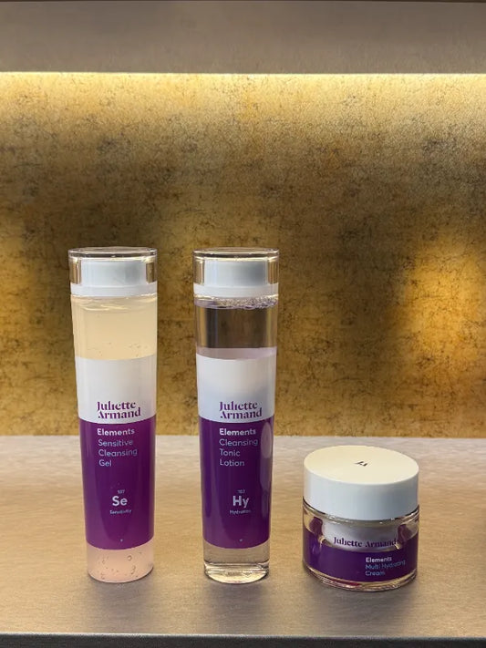 Juliette Armand Complete Elements Trio voor een vochtarme huid die trekkerig aanvoelt en behoefte heeft aan een volledige basisroutine. Te zien zijn de Sensitive Cleansing Gel 210 ml en Cleansing Tonic Lotion 210 ml in hoge transparante flacons met paars etiket, samen met de Multi Hydrating Cream 50 ml in een witte tube. De drie stappen reinigen, brengen in balans en hydrateren. Gefotografeerd als set op een warme, rustige achtergrond. Puur Diana Shop Nuenen