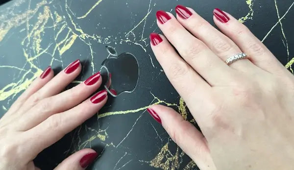 O.P.I Infinite Shine Malaga Wine, hand met wijnrode nagellak naast een laptop. Puur Diana Shop Nuenen