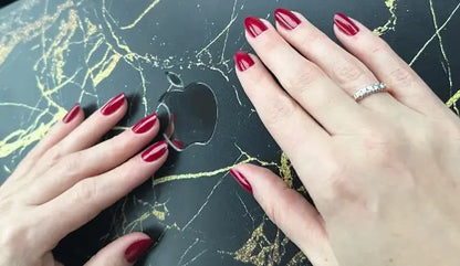 O.P.I Infinite Shine Malaga Wine, hand met wijnrode nagellak naast een laptop. Puur Diana Shop Nuenen