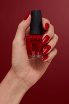 O.P.I. Nail Envy Big Apple Red, aangebracht op de hand tegen een rode achtergrond. Puur Diana Shop Nuenen